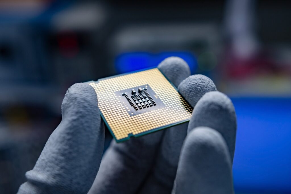 A CPU with clean, golden contacts held in the hand with some ESD gloves.
