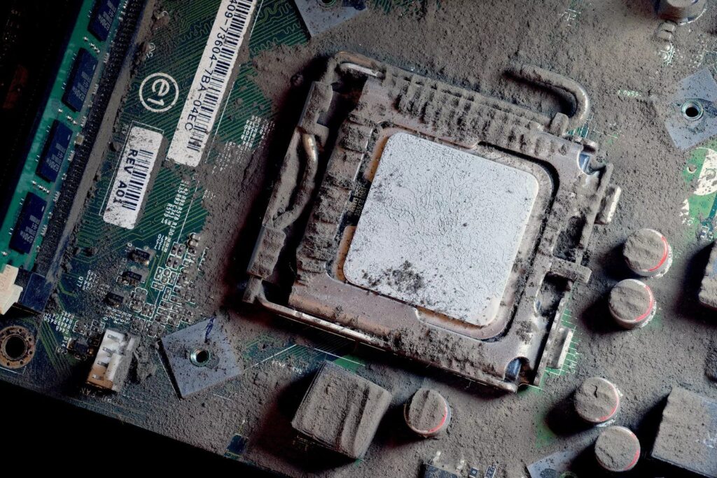 This image shows the ultimate nightmare for any PC build, a motherboard suffocating under a thick, velvet-like layer of black dust.