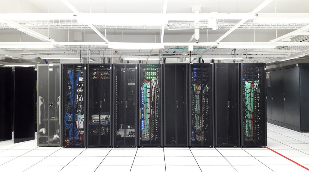Modern data center interior with rows of server racks, LED status lighting, and structured cabling in a climate-controlled environment.